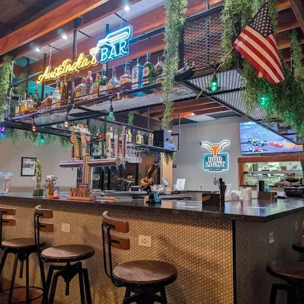 A bar with neon signs, liquor bottles, beer taps, and an American flag.